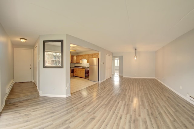 unfurnished living room featuring a baseboard heating unit, baseboards, and light wood finished floors