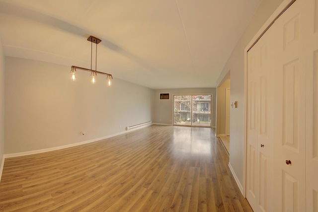 spare room with a baseboard radiator, baseboards, and wood finished floors