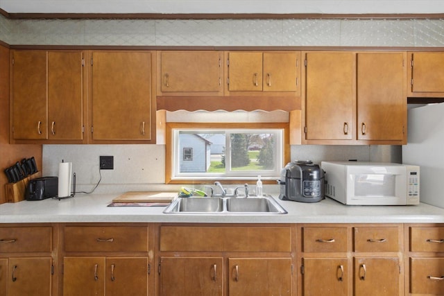 204 S Jackson Ave, Polo, IL 61064 - kitchen featuring light countertops, white microwave, brown cabinetry, and a sink