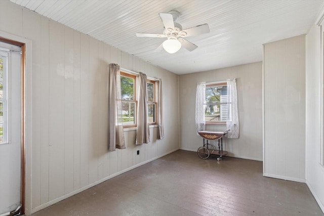 204 S Jackson Ave, Polo, IL 61064 - unfurnished room featuring wood walls, a healthy amount of sunlight, ceiling fan, and baseboards