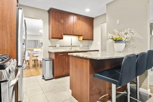 3104 Antelope Springs Rd, Northbrook, IL 60062 - kitchen featuring light stone countertops, a breakfast bar, appliances with stainless steel finishes, a sink, and a peninsula