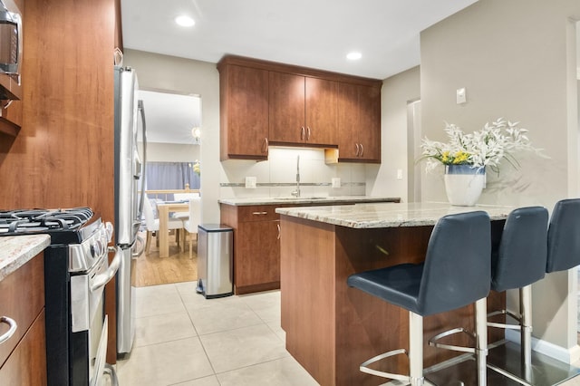 3104 Antelope Springs Rd, Northbrook, IL 60062 - kitchen featuring a breakfast bar area, a sink, appliances with stainless steel finishes, a peninsula, and brown cabinetry