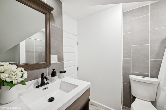 bathroom featuring tile walls, vanity, and toilet