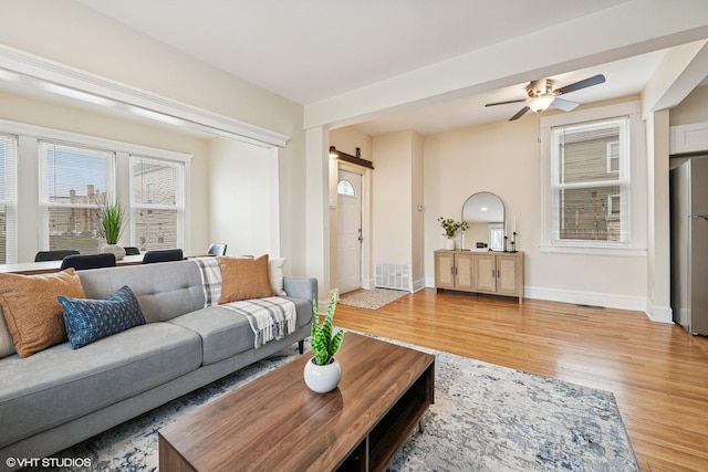 living area featuring ceiling fan, baseboards, light wood-style floors, and visible vents