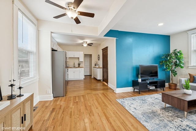 living room featuring a healthy amount of sunlight, baseboards, and ceiling fan