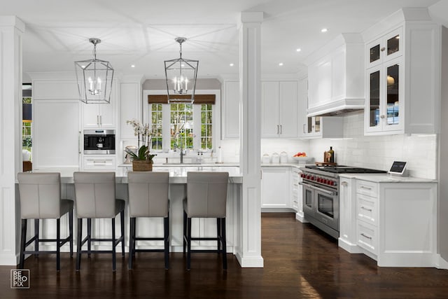 301 Canterbury Ln, Inverness, IL 60010 - kitchen featuring appliances with stainless steel finishes, backsplash, white cabinetry, a kitchen breakfast bar, and glass insert cabinets