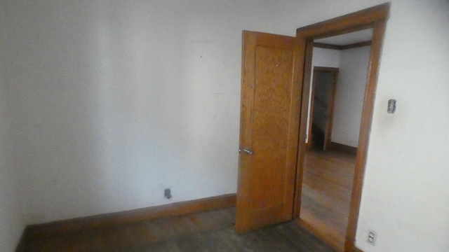 spare room with baseboards and wood finished floors