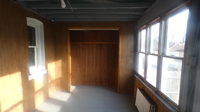 hall featuring radiator heating unit, wood walls, and plenty of natural light