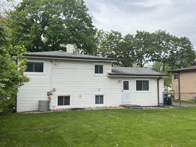 rear view of property featuring a chimney and central AC