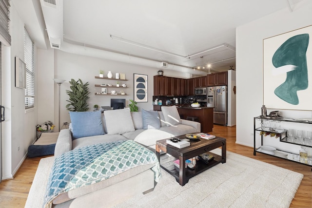 living room with light wood-style floors, attic access, visible vents, and track lighting
