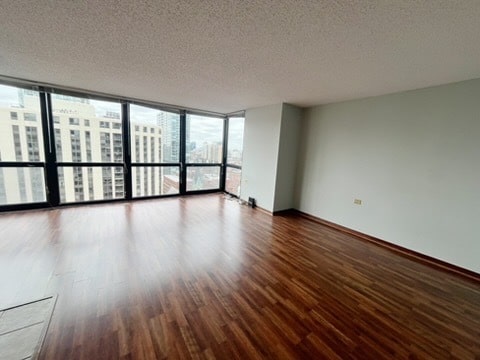 1122 N Clark St Unit 1702, Chicago, IL 60610 - spare room with dark wood-type flooring, a textured ceiling, a wall of windows, and baseboards