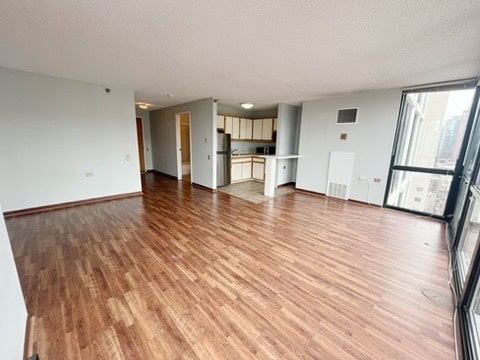 1122 N Clark St Unit 1702, Chicago, IL 60610 - unfurnished living room featuring light wood-style flooring, floor to ceiling windows, a textured ceiling, and baseboards