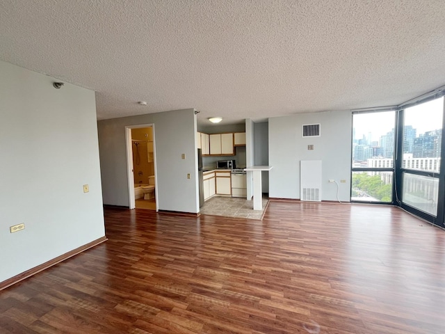 1122 N Clark St Unit 1702, Chicago, IL 60610 - unfurnished living room with wood finished floors, a textured ceiling, a wall of windows, baseboards, and a city view