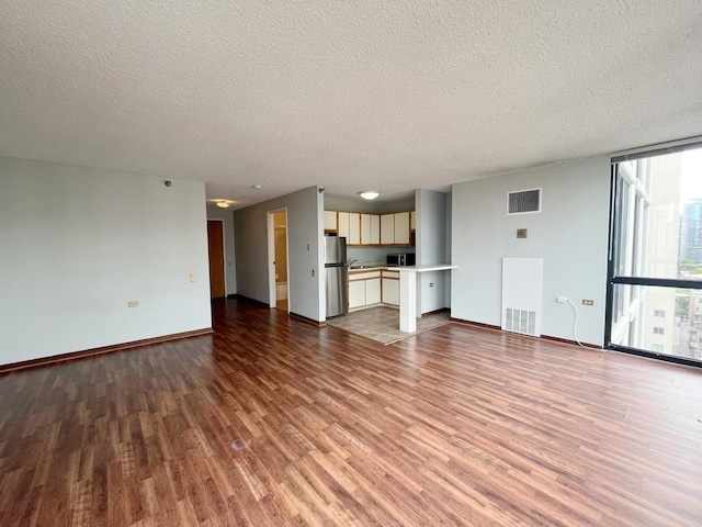 1122 N Clark St Unit 1702, Chicago, IL 60610 - unfurnished living room featuring wood finished floors, a textured ceiling, baseboards, and floor to ceiling windows