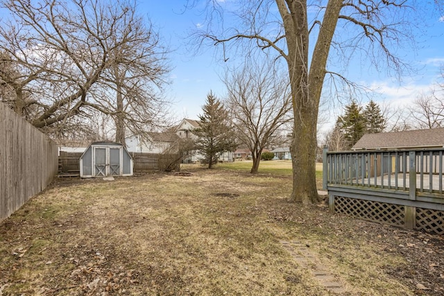 fenced backyard with a storage shed, a wooden deck, and an outdoor structure