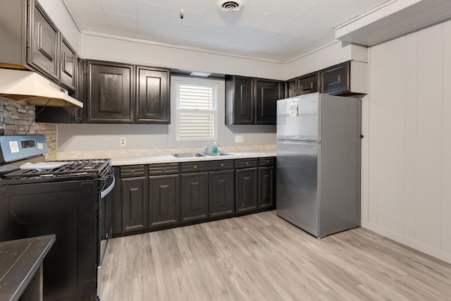 kitchen featuring freestanding refrigerator, gas stove, a sink, under cabinet range hood, and light wood finished floors