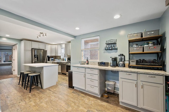 6522 S Kostner Ave, Chicago, IL 60629 - kitchen featuring a center island, a breakfast bar, light wood-type flooring, light countertops, and appliances with stainless steel finishes