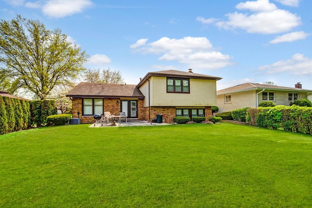 rear view of property featuring a yard, a patio area, and brick siding