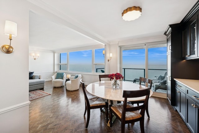 dining area featuring a water view, crown molding, and baseboards