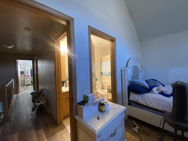 bedroom with lofted ceiling, light wood-type flooring, and ensuite bathroom
