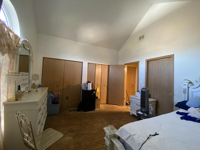 bedroom with visible vents, high vaulted ceiling, and multiple closets