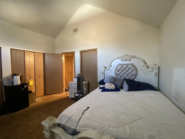 bedroom with dark wood-style flooring, visible vents, two closets, and high vaulted ceiling