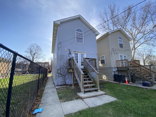 rear view of property with fence, a deck, stairs, and french doors