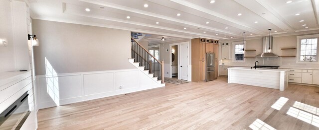 1911 S Prospect Ave, Park Ridge, IL 60068 - unfurnished living room with light wood-style floors, a tray ceiling, ornamental molding, wainscoting, and stairs