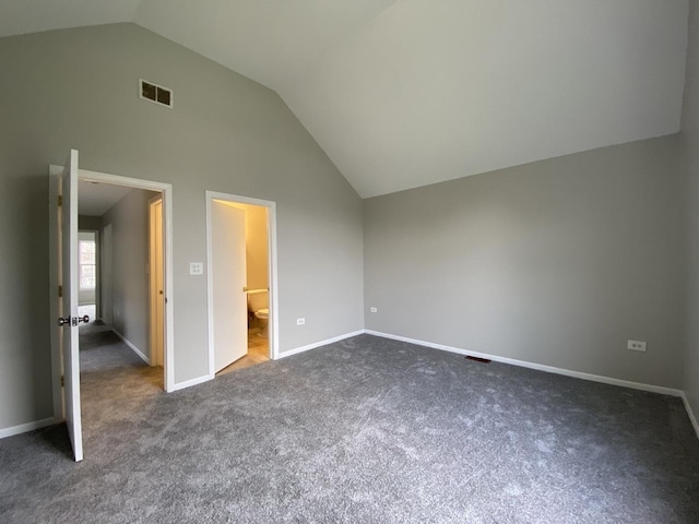 unfurnished bedroom featuring baseboards, visible vents, dark carpet, and vaulted ceiling