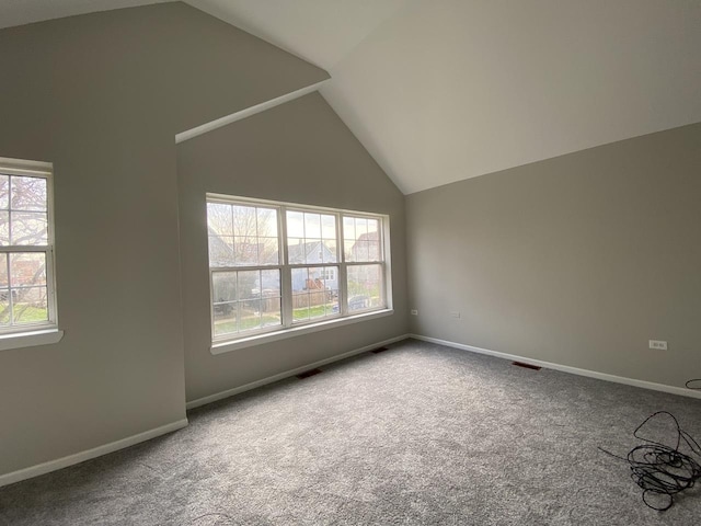 spare room featuring baseboards, visible vents, carpet floors, and vaulted ceiling