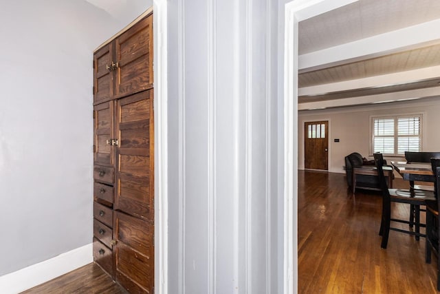 hall featuring dark wood finished floors, beam ceiling, and baseboards