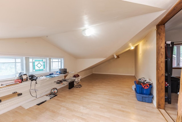 additional living space featuring wood finished floors, lofted ceiling, and baseboards