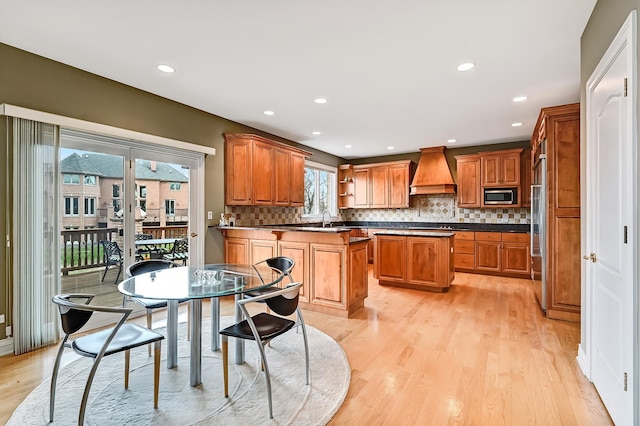 909 Prairie Ridge Ct, Burr Ridge, IL 60527 - kitchen with stainless steel appliances, custom exhaust hood, dark countertops, a sink, and light wood-style flooring