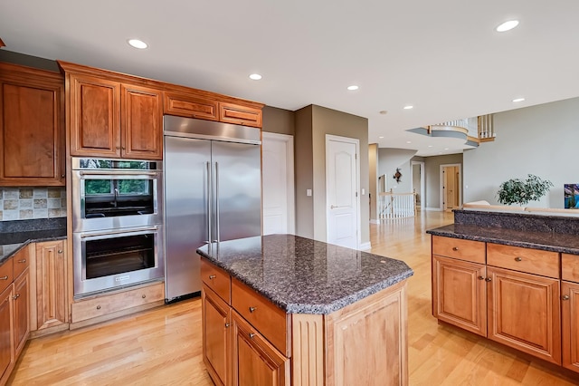 909 Prairie Ridge Ct, Burr Ridge, IL 60527 - kitchen with appliances with stainless steel finishes, light wood finished floors, recessed lighting, dark stone countertops, and a center island
