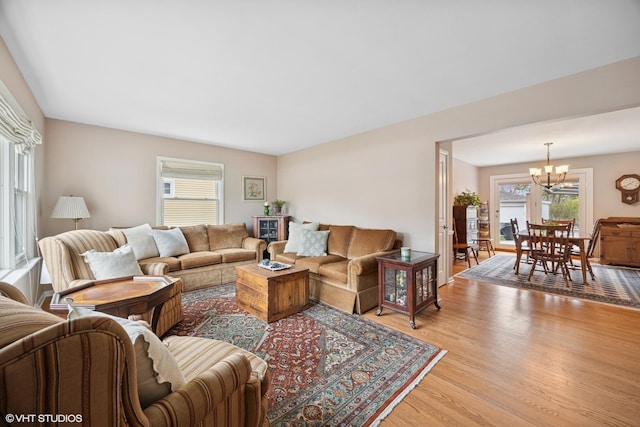 living room featuring light wood-type flooring, plenty of natural light, and an inviting chandelier