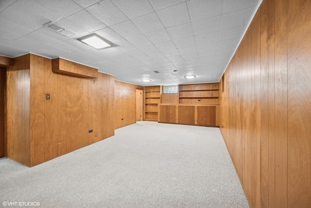 basement featuring carpet floors, visible vents, and wood walls