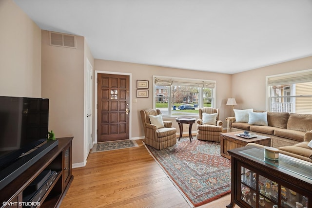 living area with light wood-style floors, visible vents, and baseboards