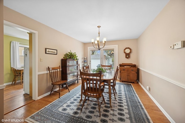 dining space with an inviting chandelier, wood finished floors, and baseboards