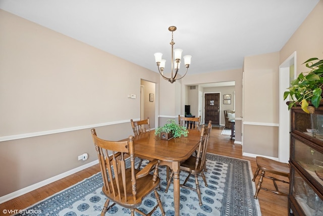 dining room with baseboards, a notable chandelier, and wood finished floors