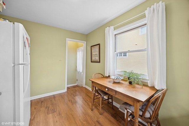 dining space with baseboards and light wood finished floors