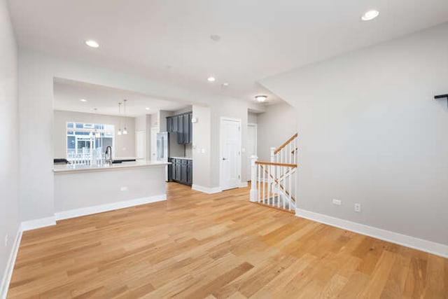 unfurnished living room featuring baseboards, light wood-style flooring, recessed lighting, and a sink
