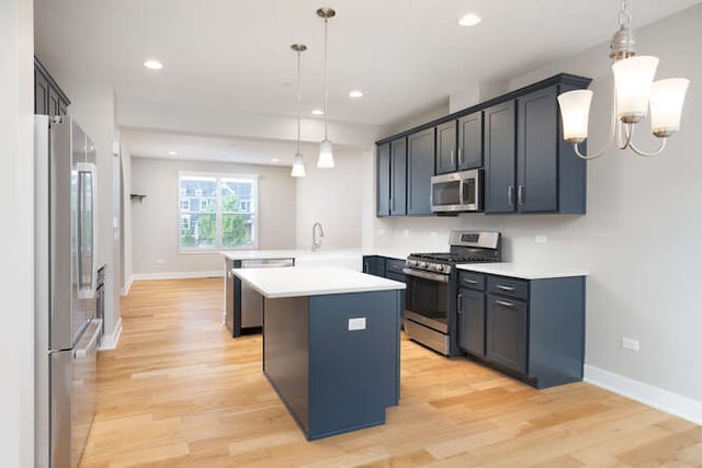 kitchen featuring appliances with stainless steel finishes, a peninsula, light countertops, light wood-type flooring, and baseboards