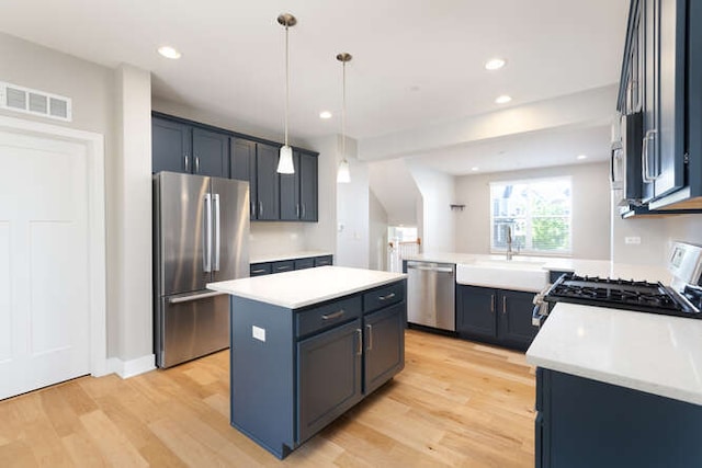 kitchen with stainless steel appliances, a sink, a kitchen island, light countertops, and recessed lighting