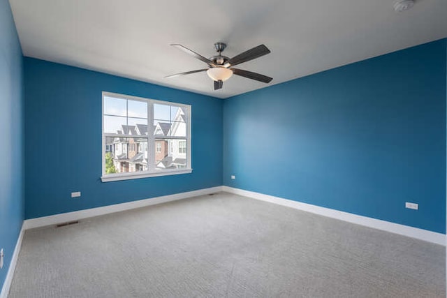 empty room featuring carpet, ceiling fan, baseboards, and a smoke detector