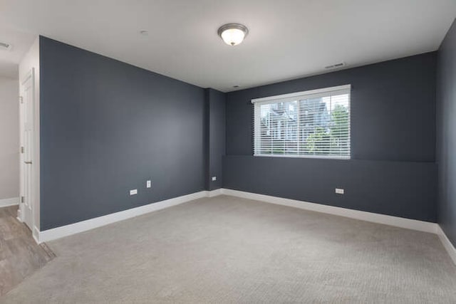 unfurnished room featuring light carpet and baseboards