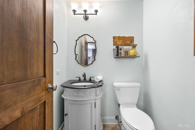 half bathroom featuring baseboards, toilet, and vanity