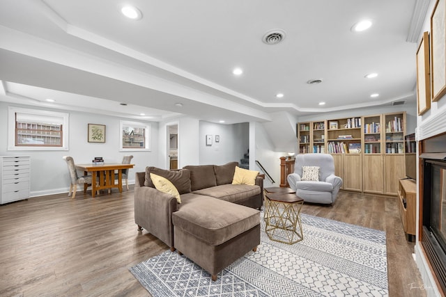living area with stairs, wood finished floors, visible vents, and a raised ceiling