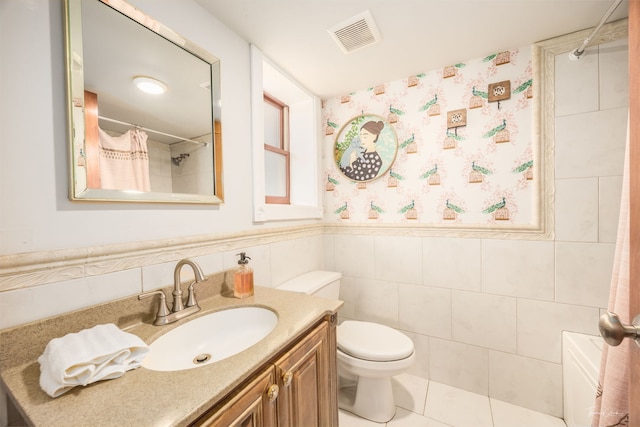 full bathroom with tile walls, a wainscoted wall, toilet, vanity, and visible vents