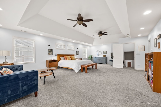 bedroom featuring recessed lighting, a tray ceiling, baseboards, and light carpet