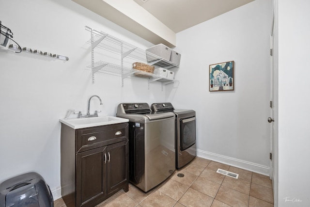 clothes washing area with a sink, light tile patterned floors, separate washer and dryer, visible vents, and baseboards